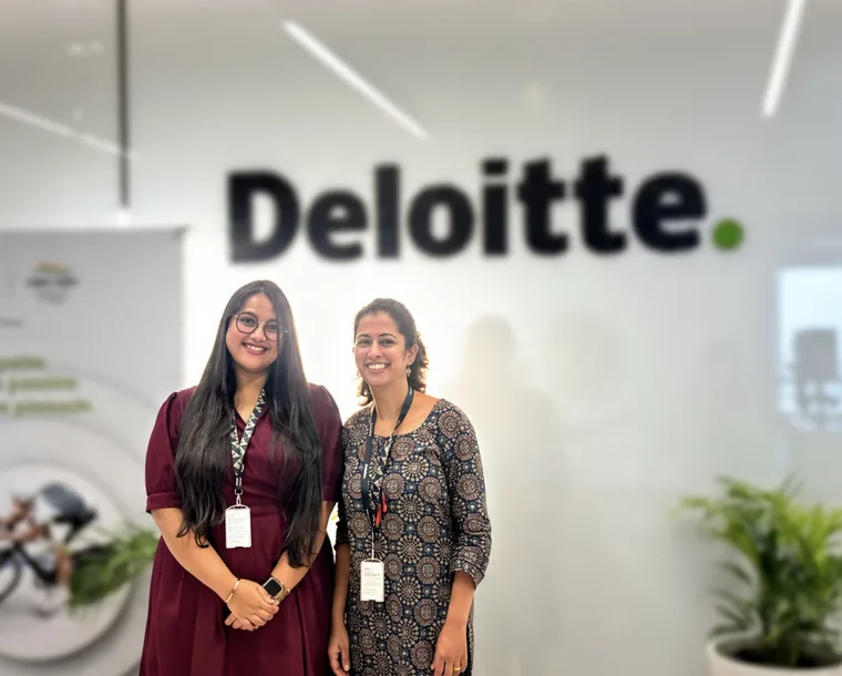 Vibha and a colleague in front of the Deloitte sign in the office.