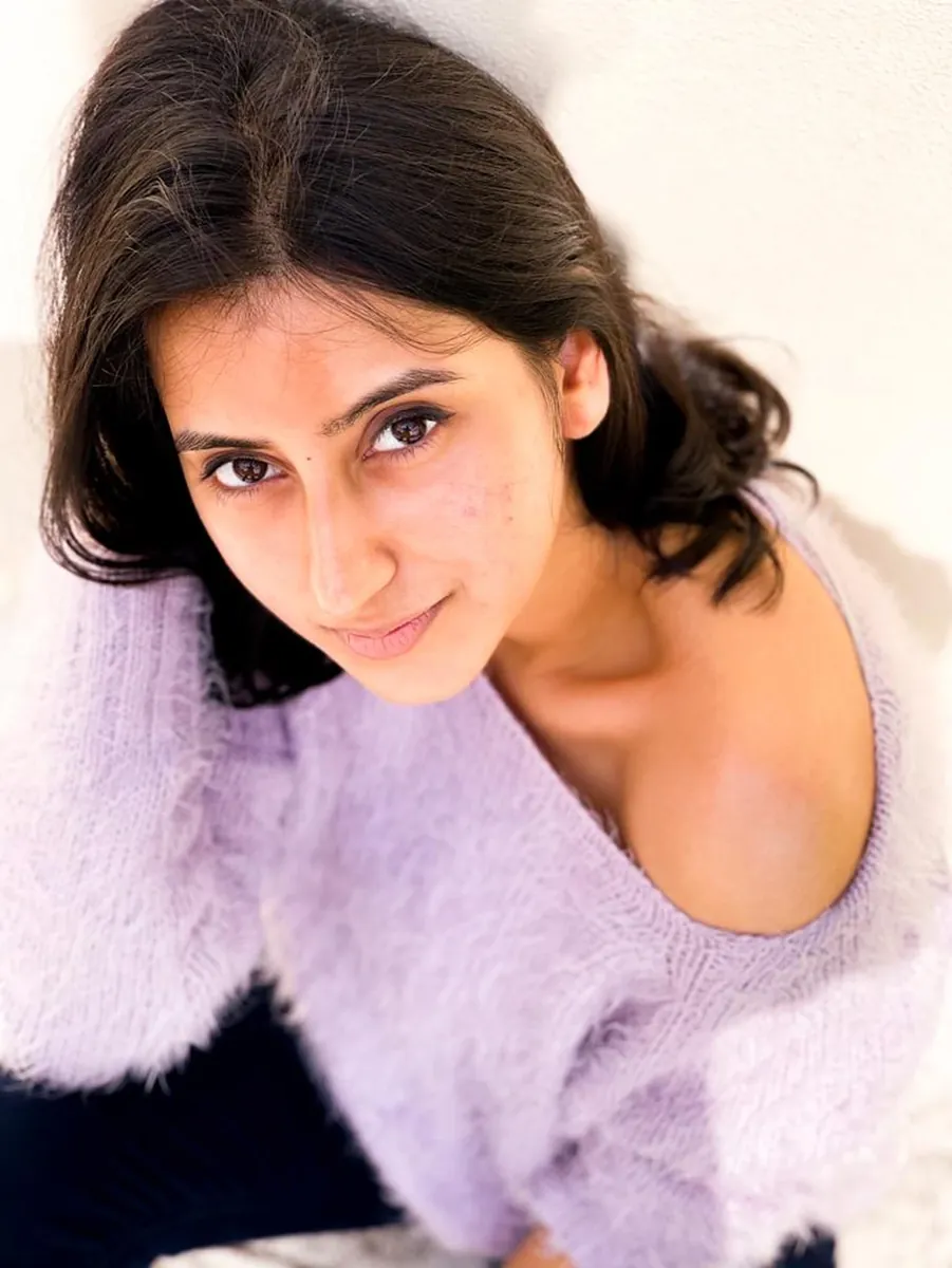A woman in a lavender sweater looking up at the camera from below.
