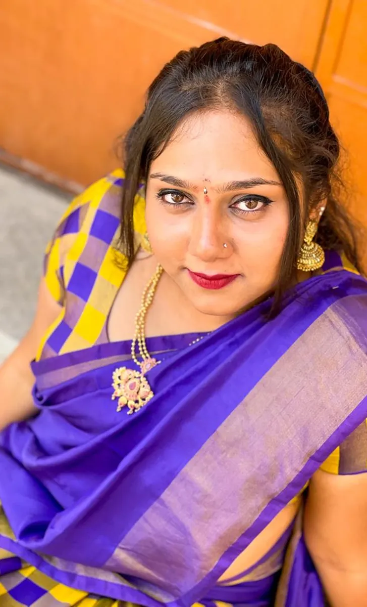 A woman in a purple and yellow sari looking up at the camera from below.