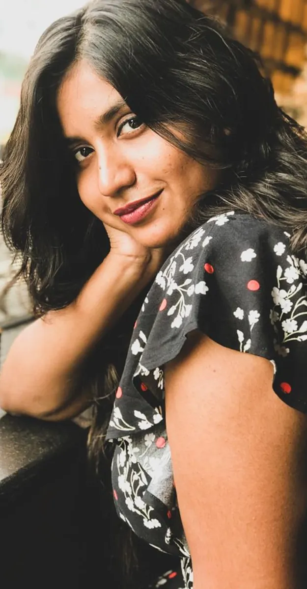 A woman glancing back over her shoulder, chin resting on her hand.