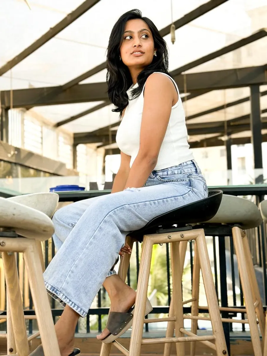 A woman on a bar stool on a rooftop, glancing away over her shoulder.